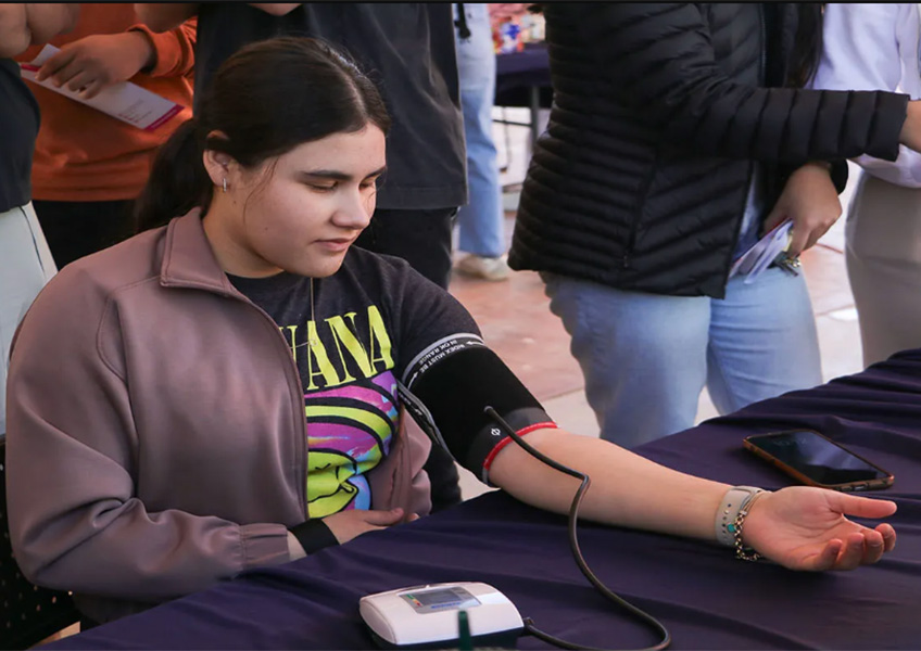 Joven sentada tomándose la presión arterial