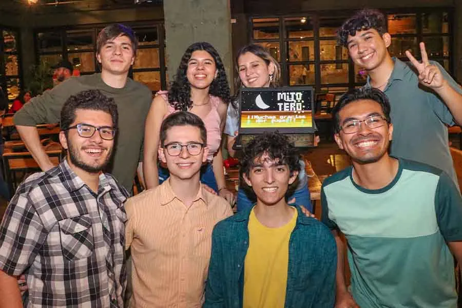 Grupo de estudiantes sosteniendo una laptop que muestra la pantalla de inicio de un videojuego de su propia autoría.