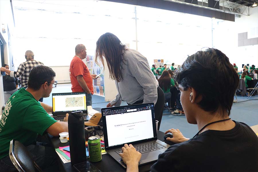 Tres personas alrededor de una mesa, trabajando en laptops.