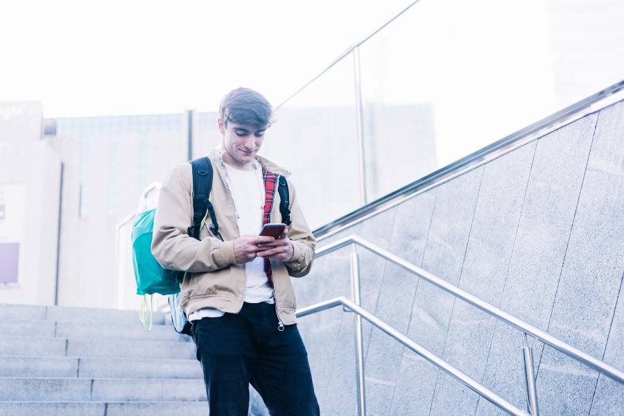 Joven consultando su celular y sonriendo