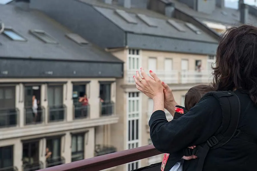 Mujer con su beb&eacute; en su balc&oacute;n aplaudiendo a personal que lucha contra el COVID-19