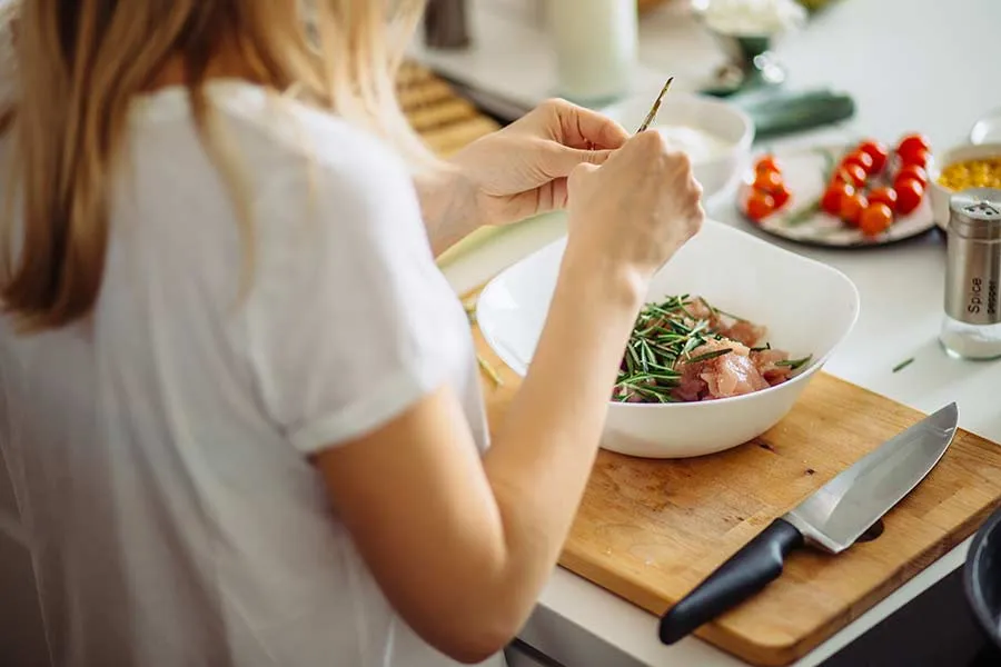 Silueta de una chica cortando verduras en la cocina