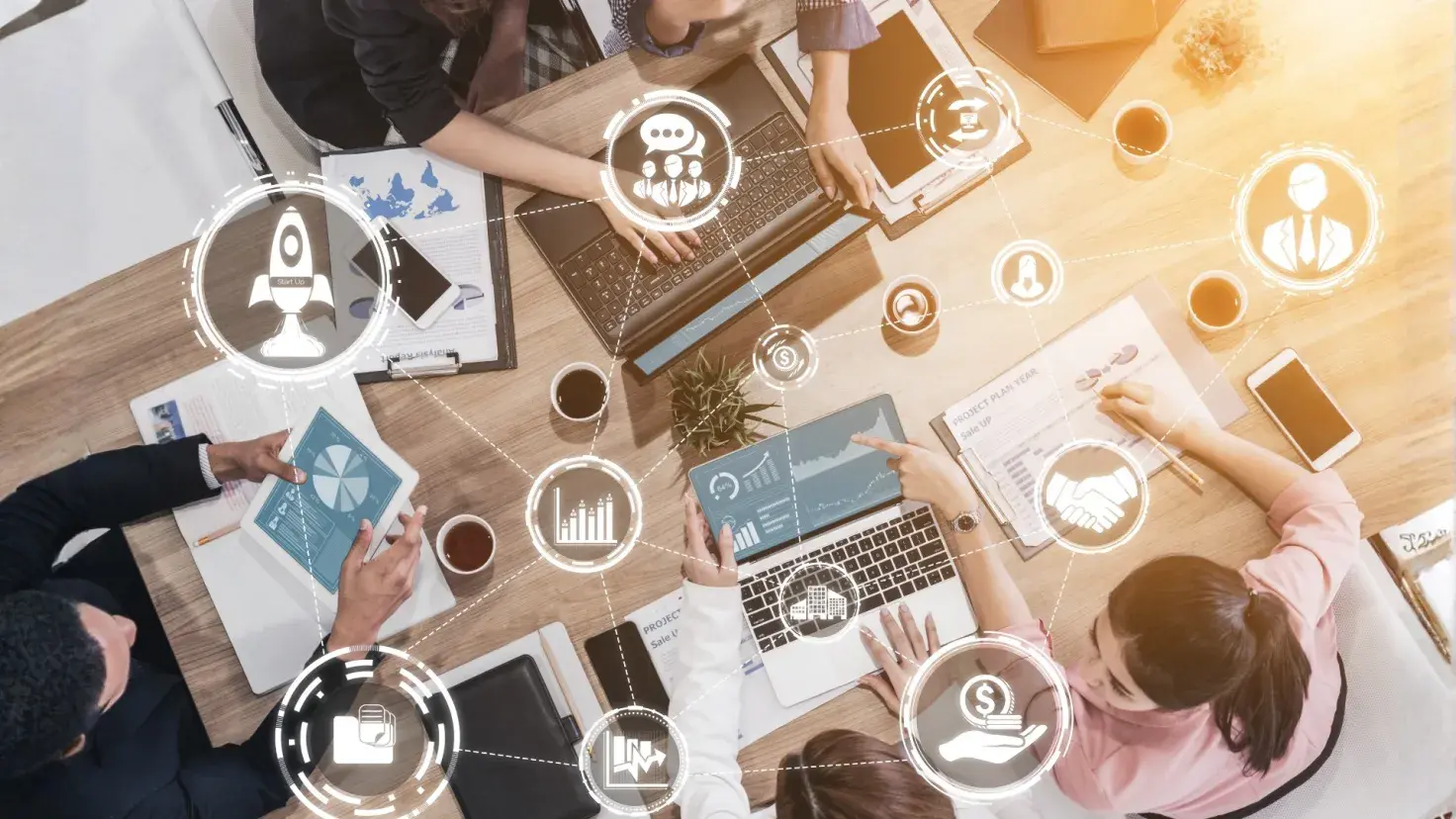 Equipo de emprendedores colaborando en una mesa con laptops, gráficas y herramientas digitales, analizando ideas de negocio y crecimiento