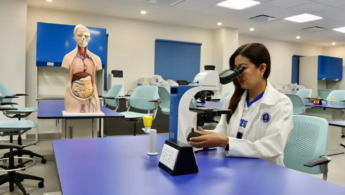 Karla Rojas observa una muestra a través de un microscopio en un laboratorio académico.