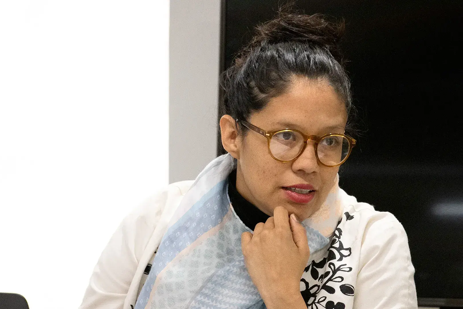 Profesora con lentes, ropa blanca y el cabello sujetado