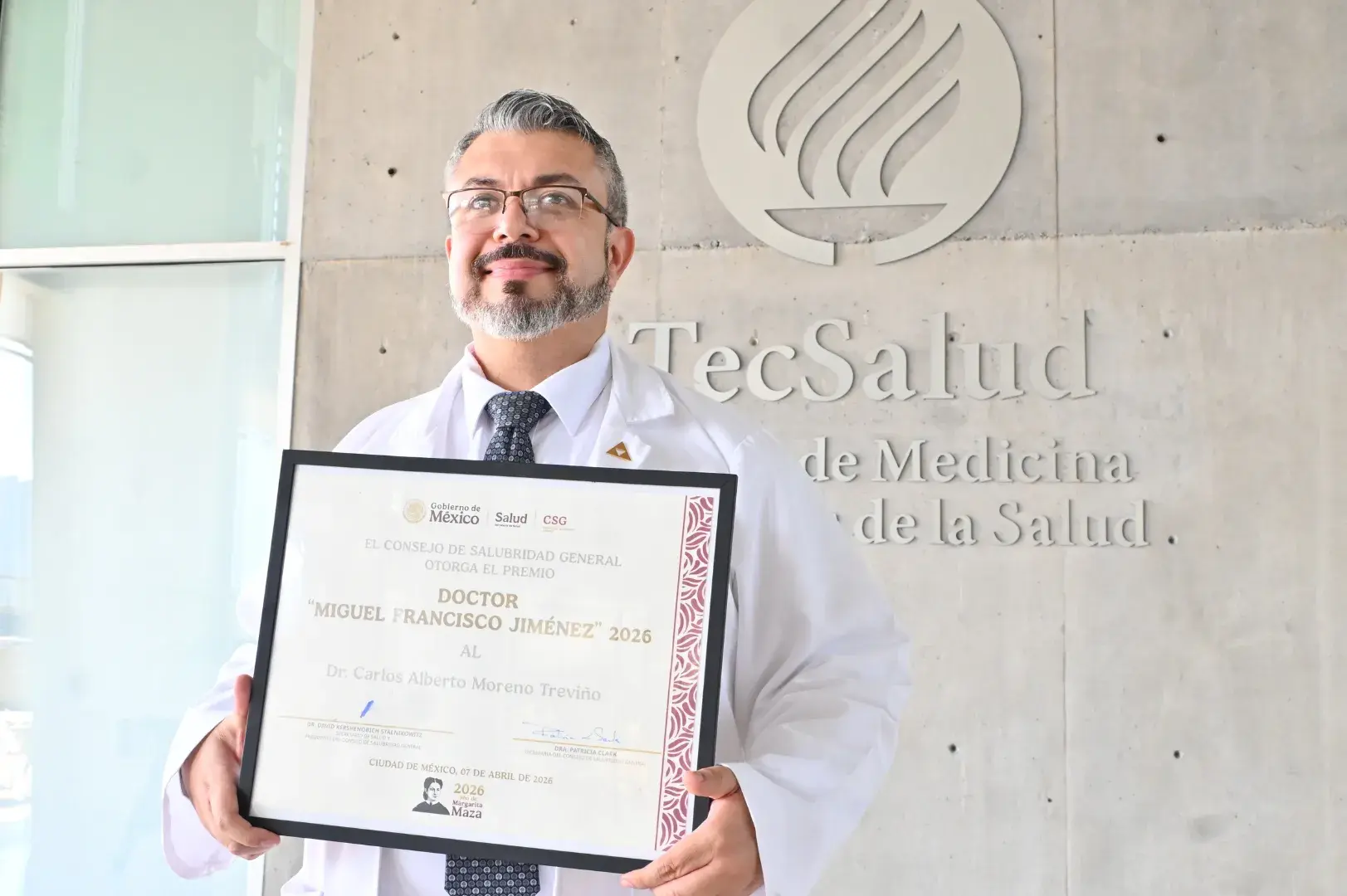 Doctor Carlos Moreno posando con su Premio Dr. Miguel Francisco Jiménez 2026 frente a la EMIS del Tec