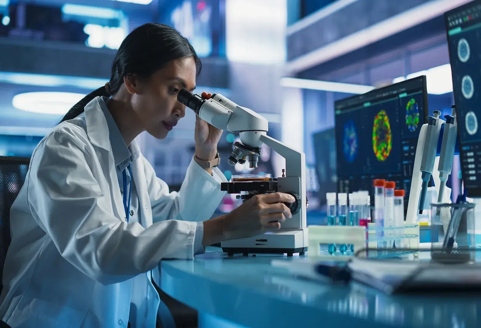 mujer en laboratorio viendo por microscopio