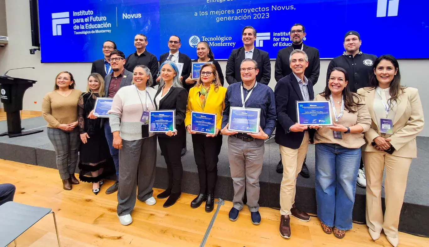 Grupo de docentes y directivos del Tecnológico de Monterrey posan con sus reconocimientos NOVUS durante la ceremonia de entrega a los mejores proyectos de innovación educativa generación 2023, en el marco de IFE Conference, frente a una pantalla institucional.
