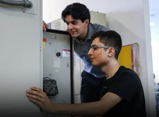 Dos estudiantes analizan los circuitos de una caja.