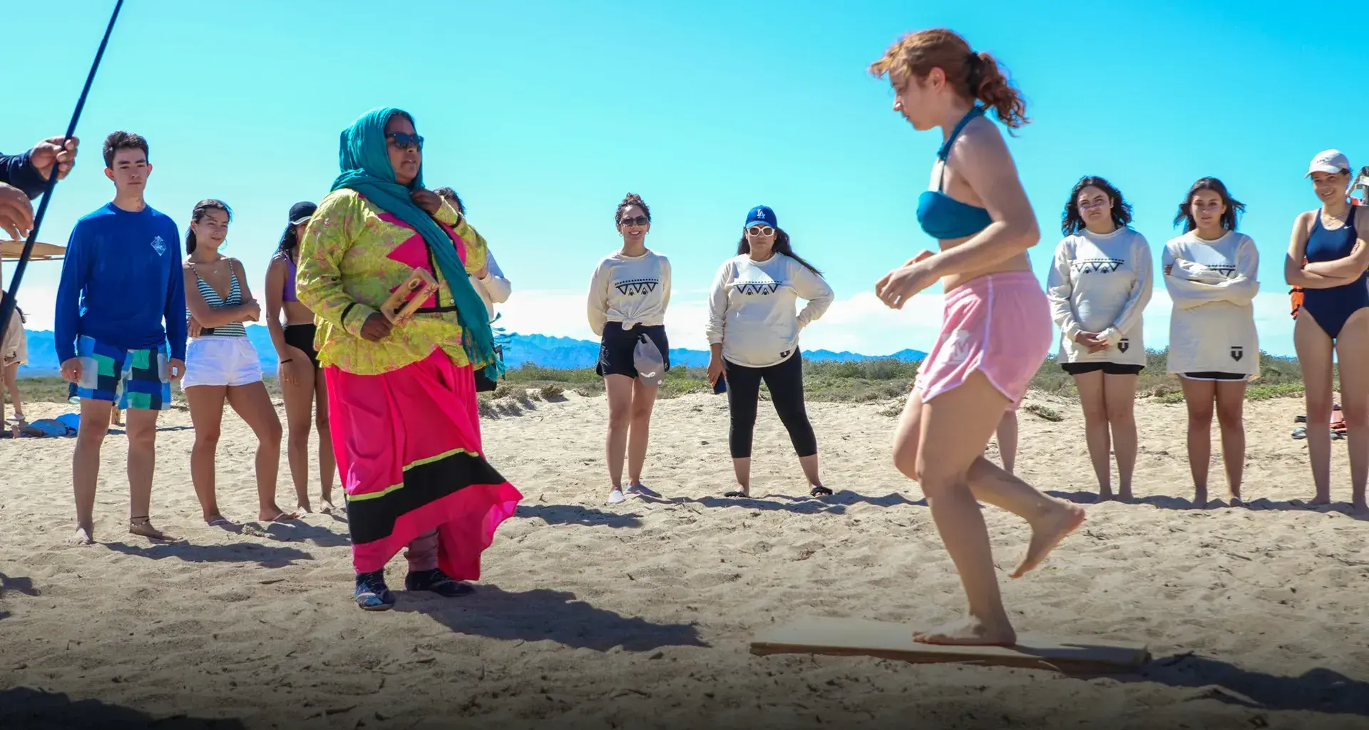 Adolescente hace baile tradicional guiada por un miembro de la comunidad Comca'ac en la playa.