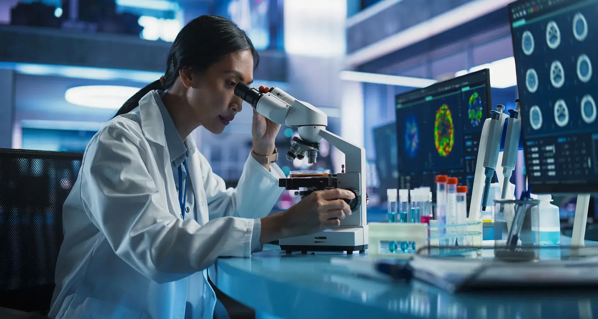 mujer en laboratorio viendo por microscopio