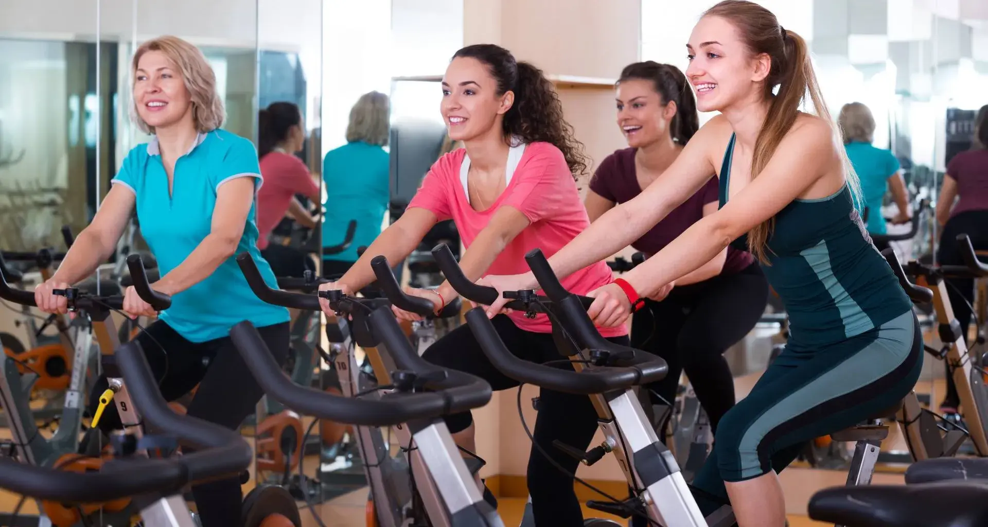 Mujeres de distintas edades realizando spinning en un gimnasio