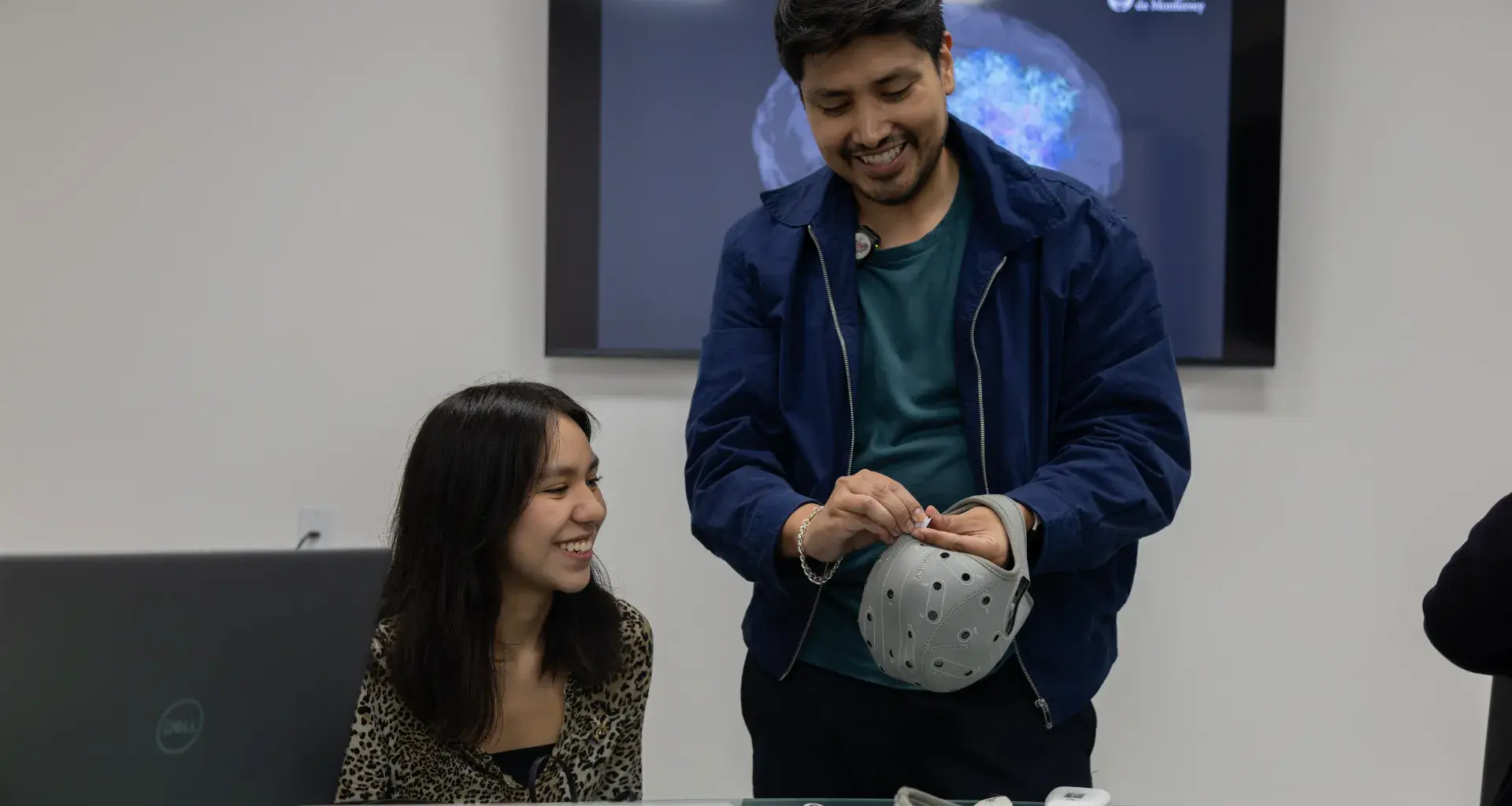 Un profesor del Tec CCM ajustando un casquete de electroencefalograma (EEG) en la cabeza de un estudiante dentro del MKT Research Lab.