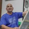 Profesor de artes plásticas pintando un cuadro con ligera sonrisa volteando hacia arriba.