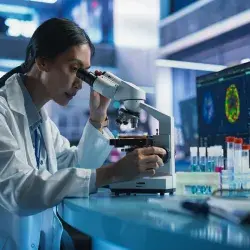 mujer en laboratorio viendo por microscopio