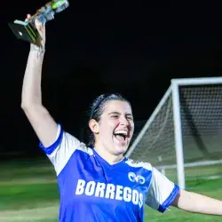 Jugadora de Borregos Laguna con uniforme azul y blanco festeja con el trofeo de primer lugar el campeonato femenil de fútbol soccer