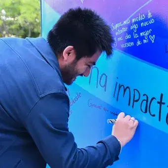 Alumno escribiendo en mural.