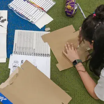 Joven acostada en el piso trabajando en manualidades.