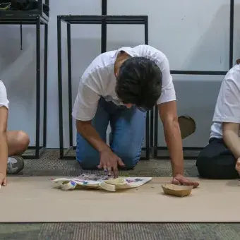 Tres jóvenes dibujando sobre papel kraft.
