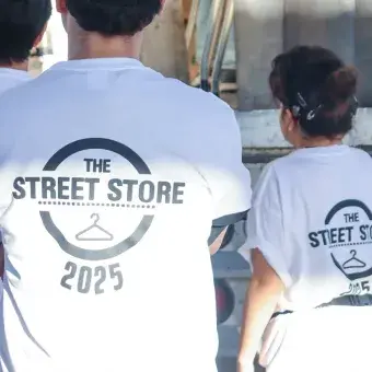 El grupo de liderazgo Athena de PrepaTec Sonora Norte organizó la sexta edición de Street Store. Foto: Emilio Morales Vista de espaldas de tres voluntarios portando camisetas blancas con un logo que dice Street Store 2025.