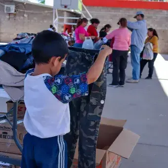 Más de 800 personas fueron beneficiadas. Foto: Helena Armenta. Niño sosteniendo par de pantalones.
