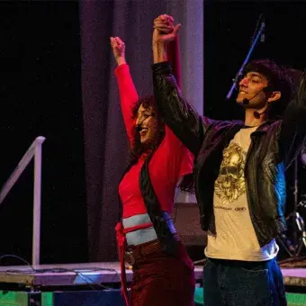Foto: Diego Beltrán Un chico y una chica en escenario se toman de la mano con brazos alsados para saludar al público.