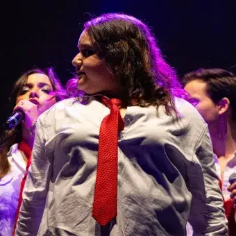 Foto: Blas Murillo Chica vestida estilo colegial cantando en el escenario volteando hacia la izquerda.