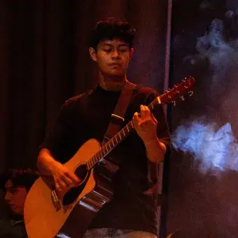 Foto: Blas Murrillo Chico tocando la guitarra acústica en escenario con humo alrededor.