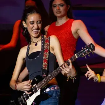 Foto: Blas Murillo Chica tocando la guitarra eléctrica en escenario con humo alrededor.