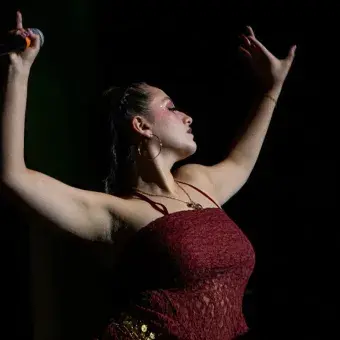 Foto: Blas Murillo Mujer vestida de rojo sosteniendo ambos brazos en el aire en posición de belly dance.