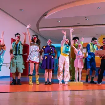 Actores con vestuarios y narices de payaso saludando al público.