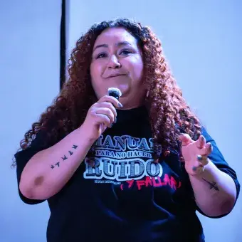 Mujer hablando mientras sostiene un micrófono. 