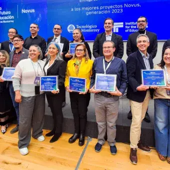 Grupo de docentes y directivos del Tecnológico de Monterrey posan con sus reconocimientos NOVUS durante la ceremonia de entrega a los mejores proyectos de innovación educativa generación 2023, en el marco de IFE Conference, frente a una pantalla institucional.